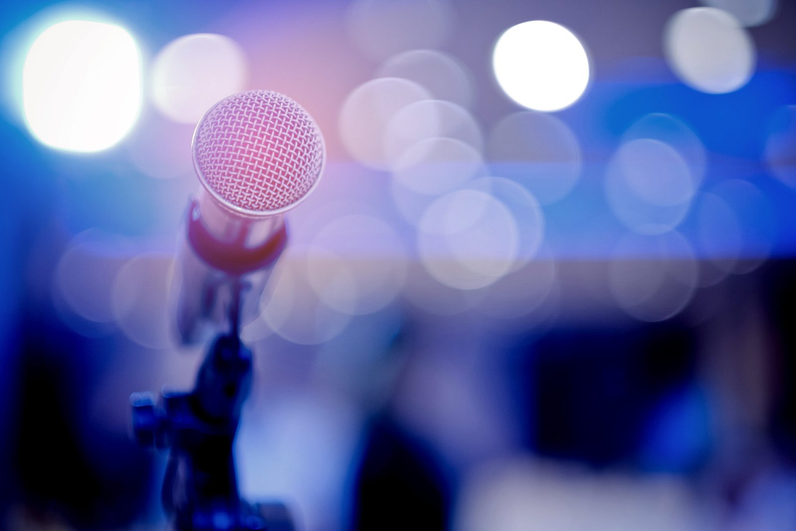 The view from behind a microphone with a blurred out audience.