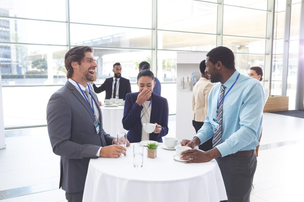 Business people interacting with each other at table with cups of tea/coffee during an event