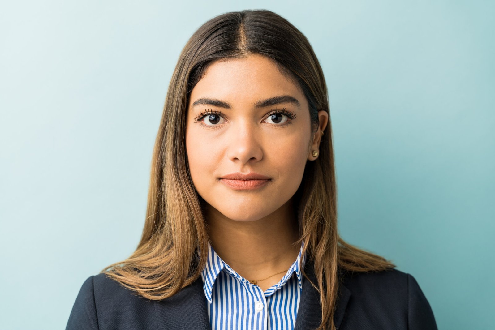 Headshot of a young Latina woman with straight hair wearing business attire.