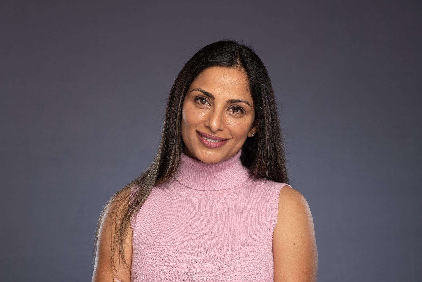 Smiling Indian woman in business attire with long straight hair.